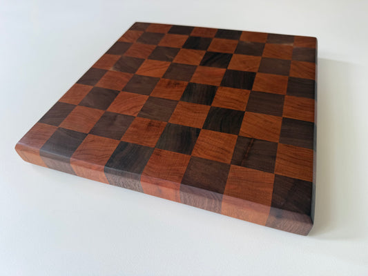 Square cutting board with a checkered cherry and walnut wood design