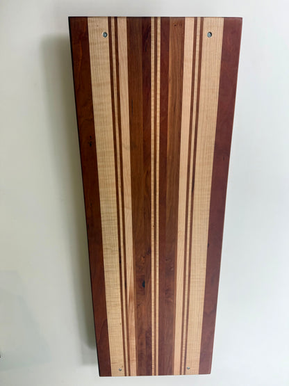 The back of a rectangular wooden serving board with a striped pattern of light and dark wood tones